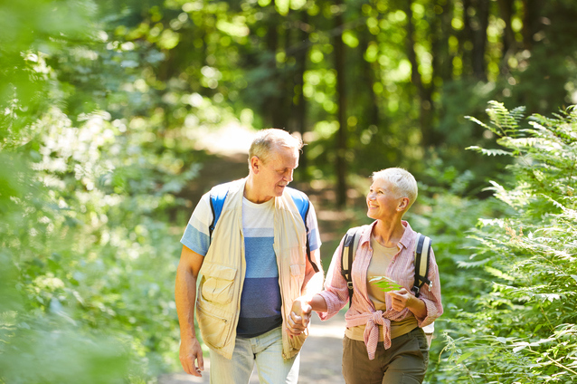Older couple walking together in a wooded area