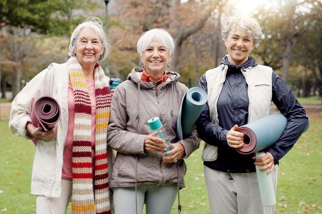 Three senior women with yoga mats in a park