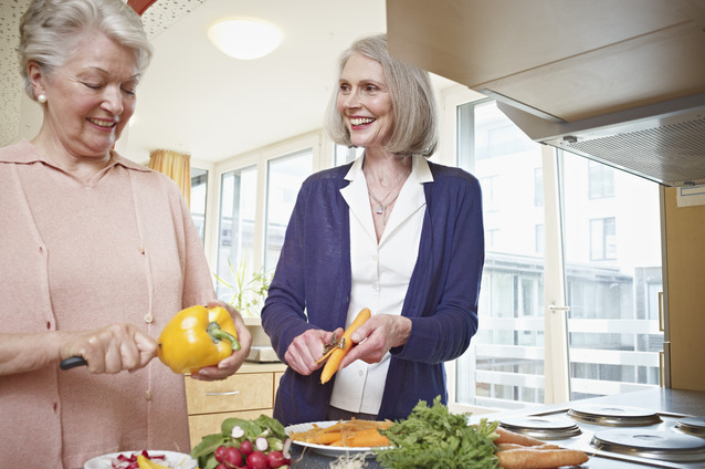 Two women preparing vegetables in a kitchen