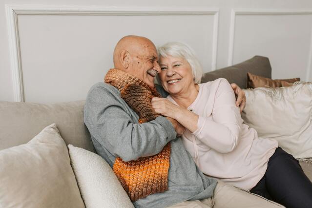 Two seniors sharing a joyful moment on a couch.