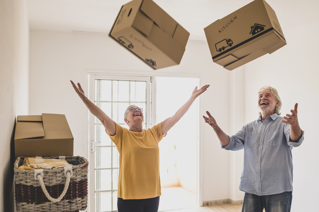 Seniors joyfully tossing moving boxes indoors