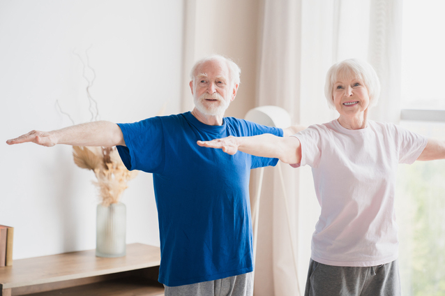 Two seniors engaged in light exercise indoors.