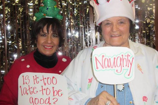 Two residents in festive outfits holding funny signs.