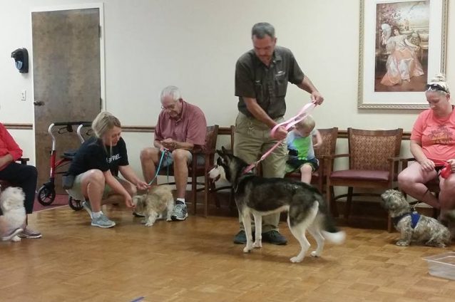 Residents engaging in a pet therapy session indoors.