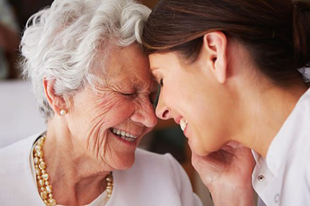 An elderly woman and caregiver sharing a joyful moment.