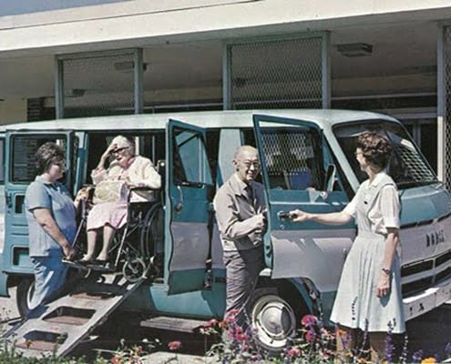 Residents and staff interacting at a facility vehicle.