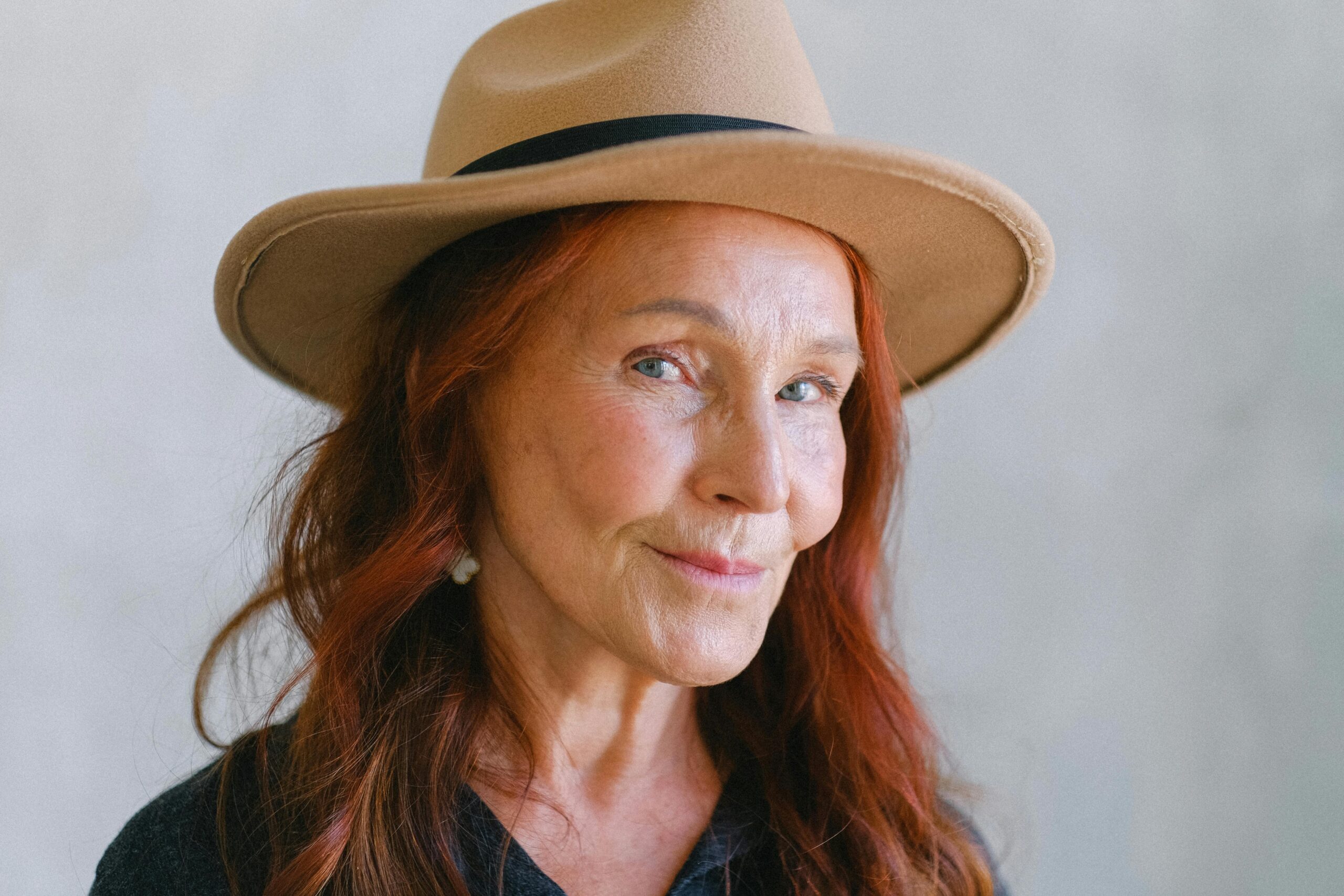 Portrait of an older woman with red hair and a hat.