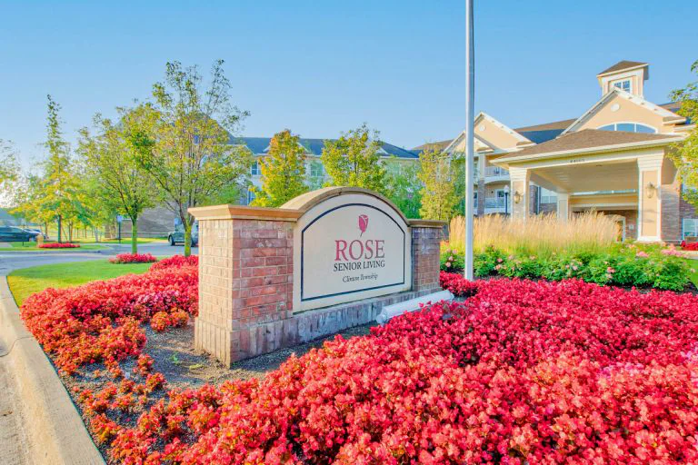 Exterior sign of Rose Senior Living surrounded by flowers