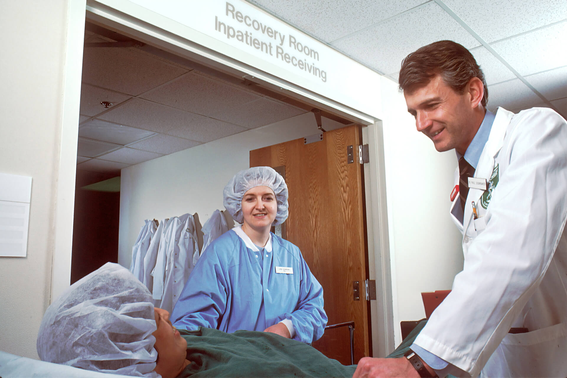 Medical staff interacting with a patient in a recovery room.