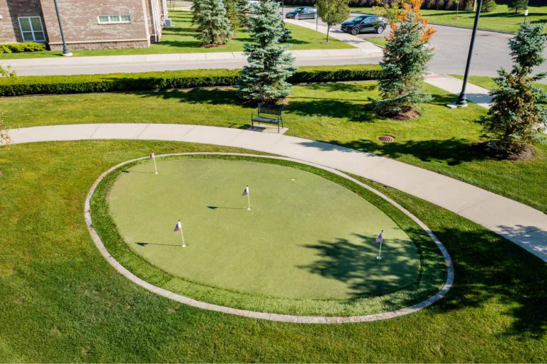 Outdoor putting green surrounded by landscaping.