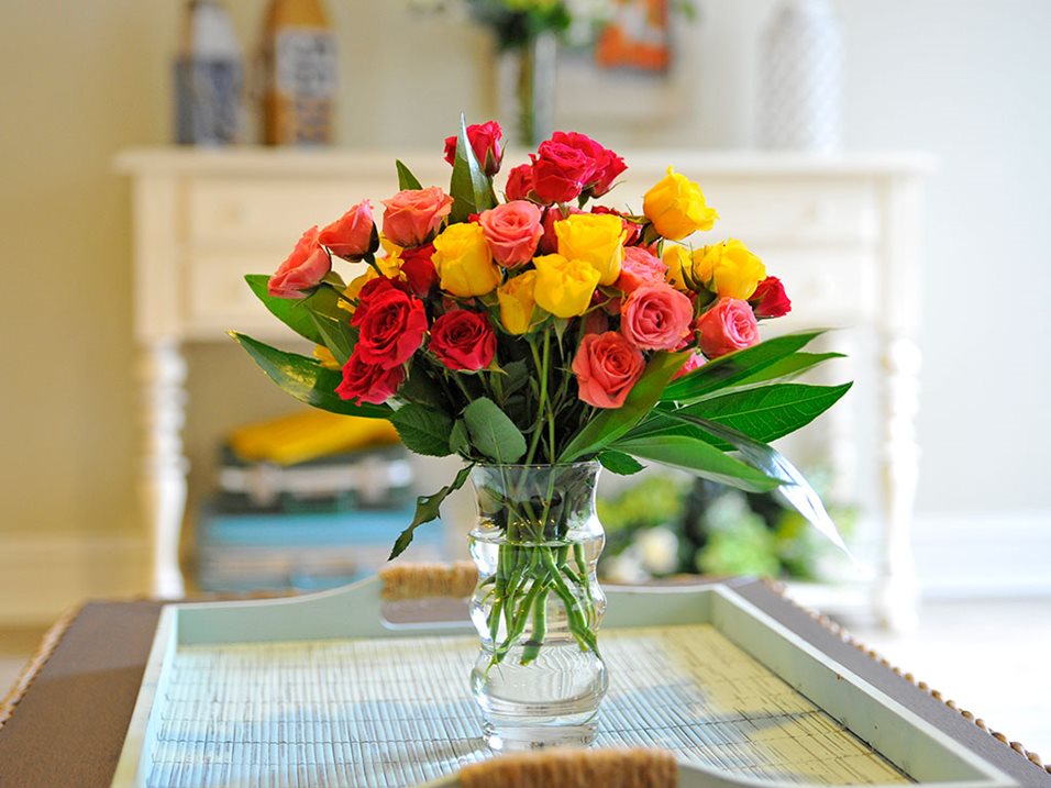 Vibrant bouquet of roses in a glass vase on a table.