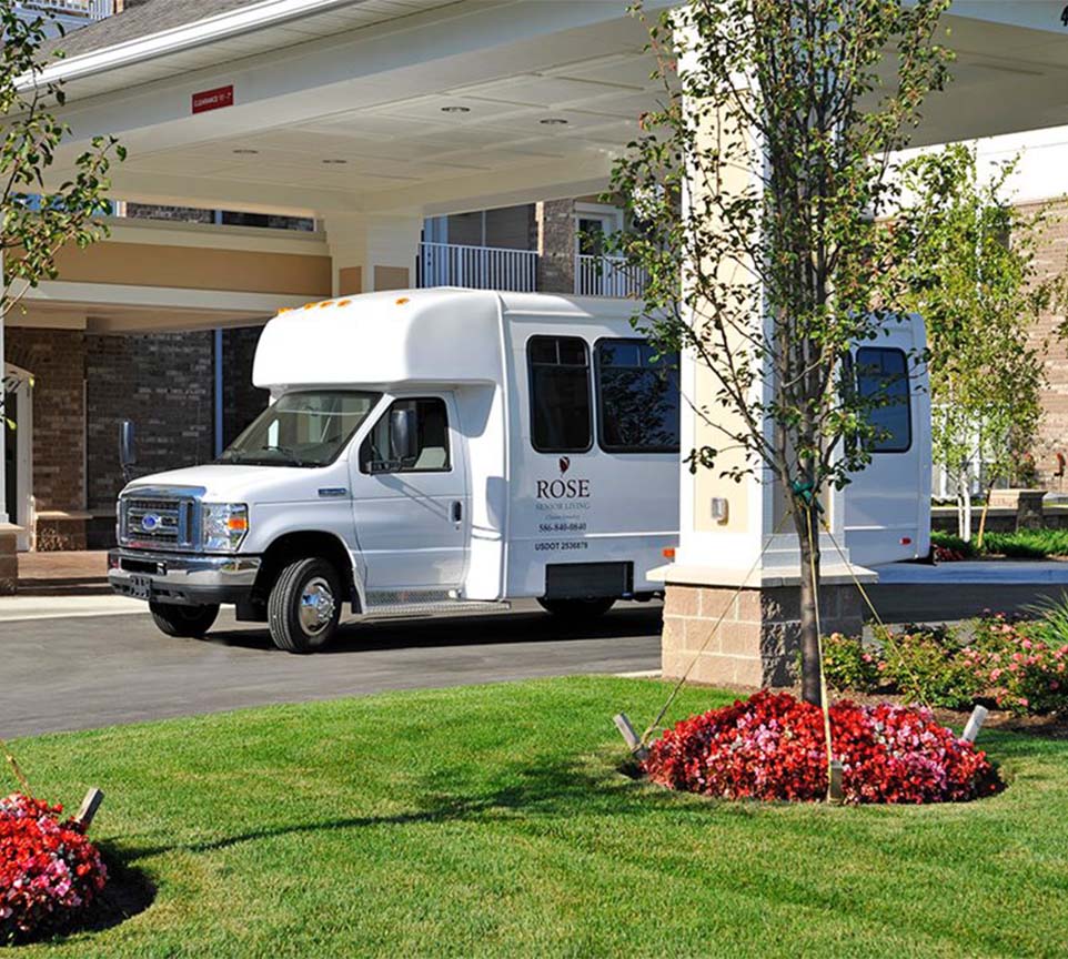 Facility shuttle bus near entrance and flowers.