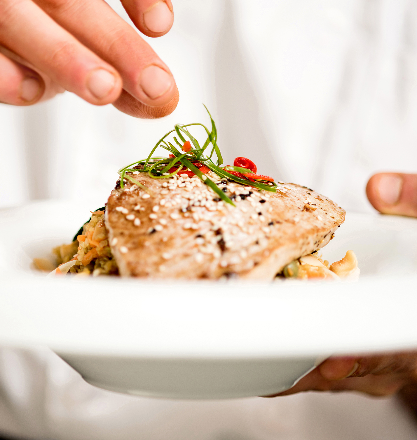 Close-up of a chef plating a gourmet dish.