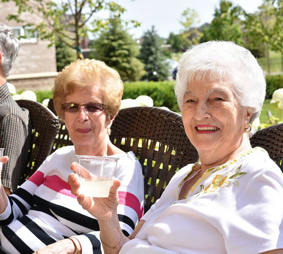 Two elderly women enjoying drinks outdoors.