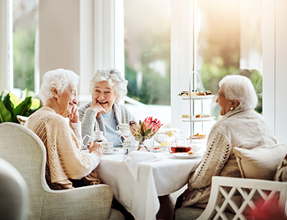 Three women enjoying tea together in a bright room.