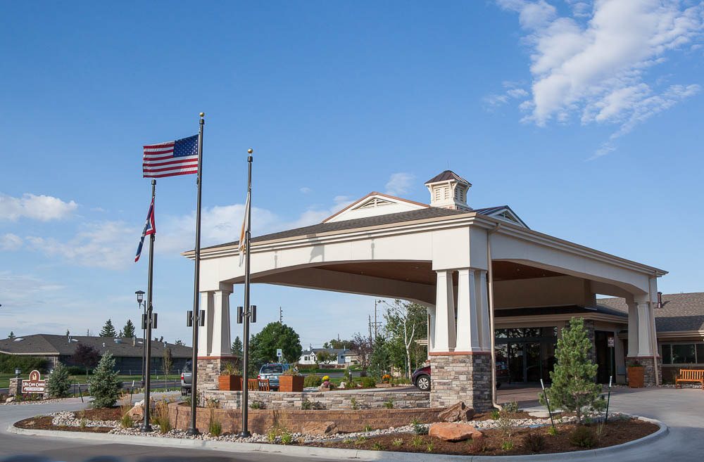 Entrance of a senior living facility with flags and architecture