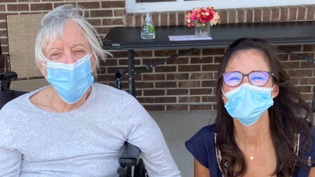 Two masked individuals smiling outside the facility