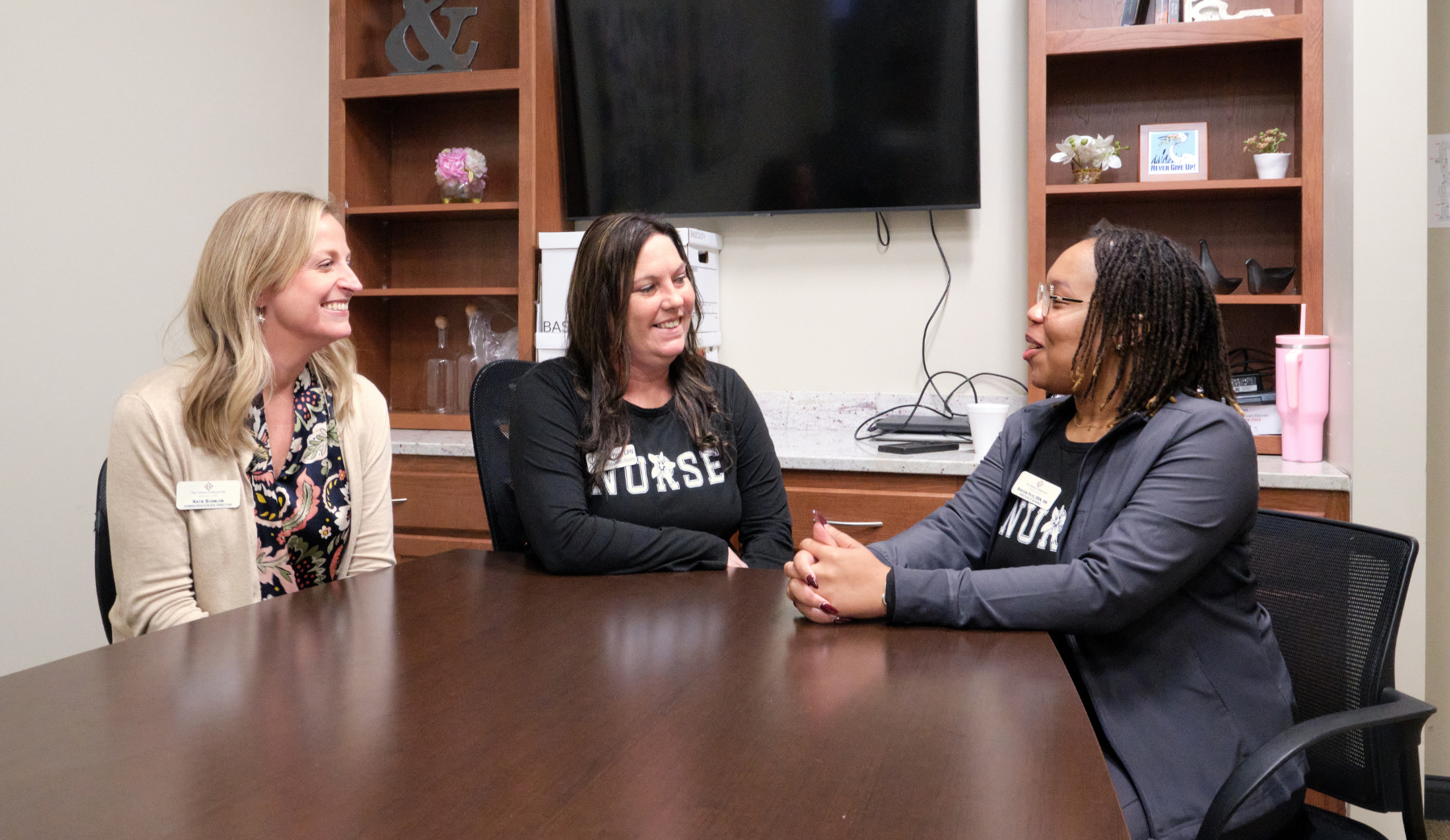 Three staff members engaged in conversation at a table