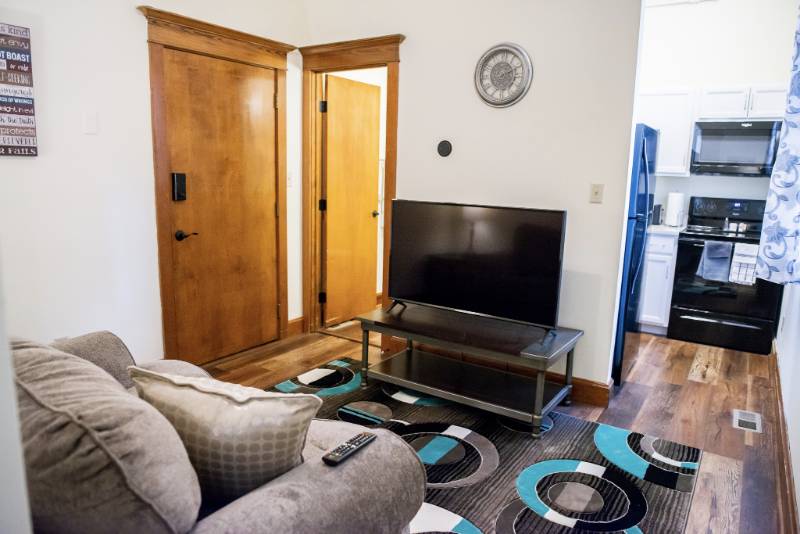 Cozy living room area with a TV and kitchen visible