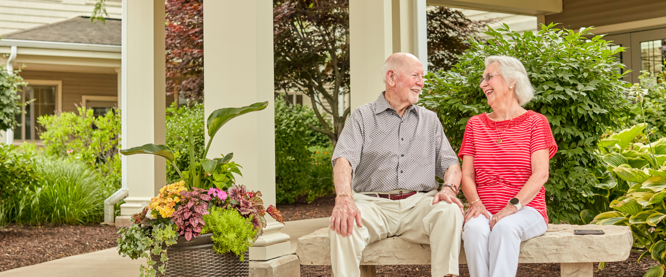 Two residents smiling together on a bench outside