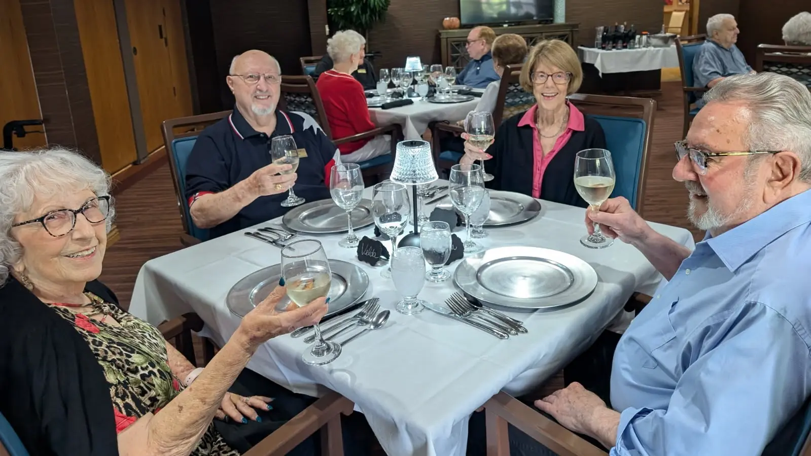 Residents toasting over a dining table with drinks