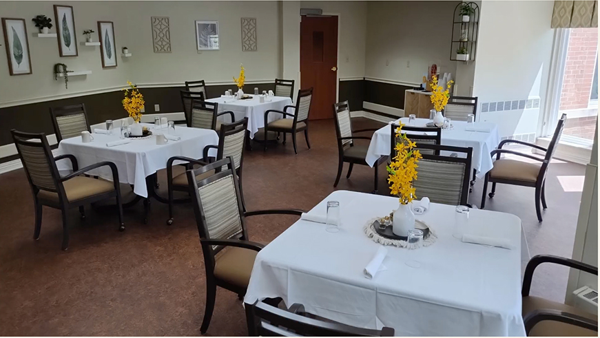 Bright dining room with neatly set tables and flowers