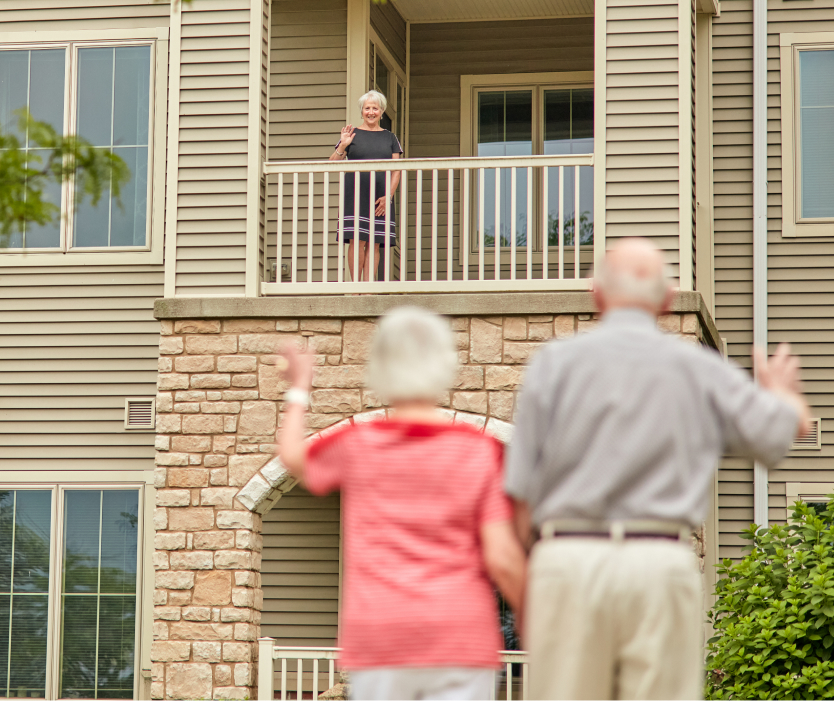 Residents waving from a balcony to another resident