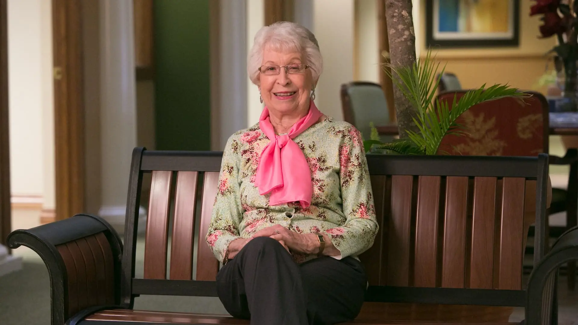 Resident smiling on a bench in a common area
