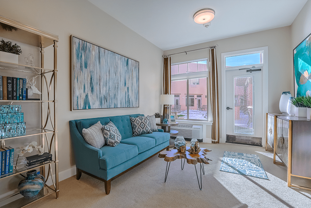 Bright and cozy common area with a teal couch