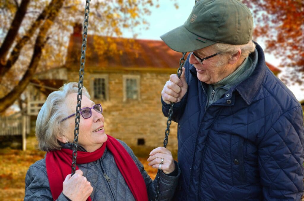 Elderly couple enjoying a moment on swings in a garden