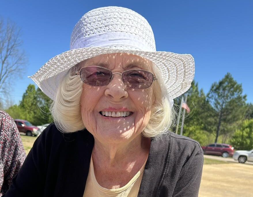 Senior woman smiling outdoors in a sunhat
