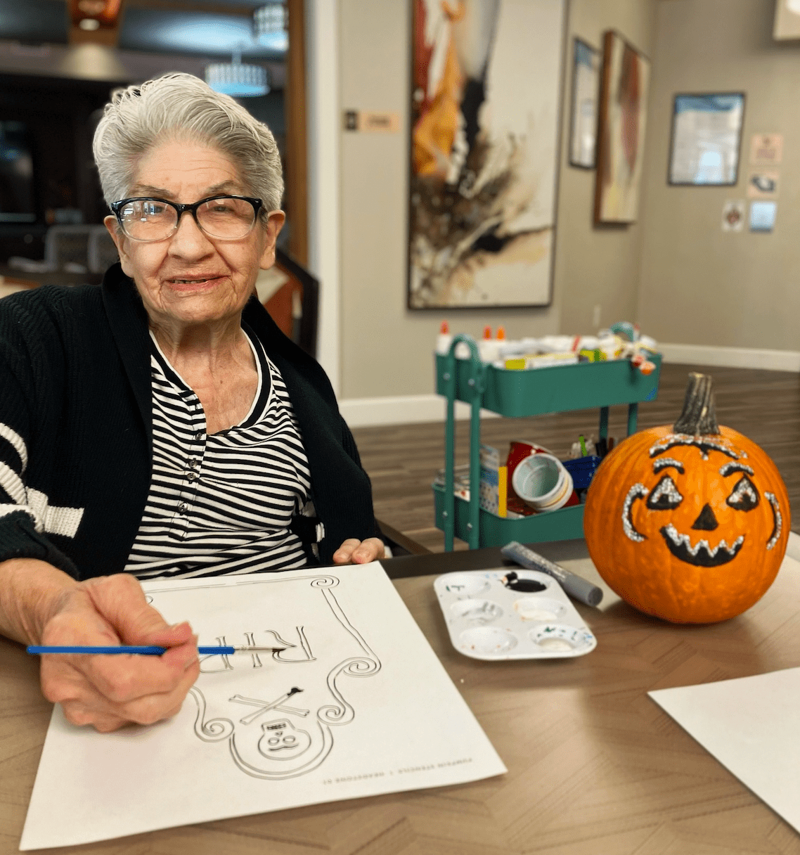 Resident engaged in art activity with a decorated pumpkin