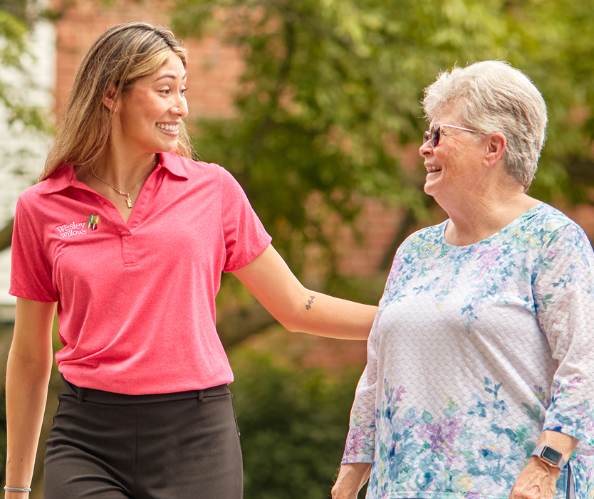 Staff member walking with a resident in the garden