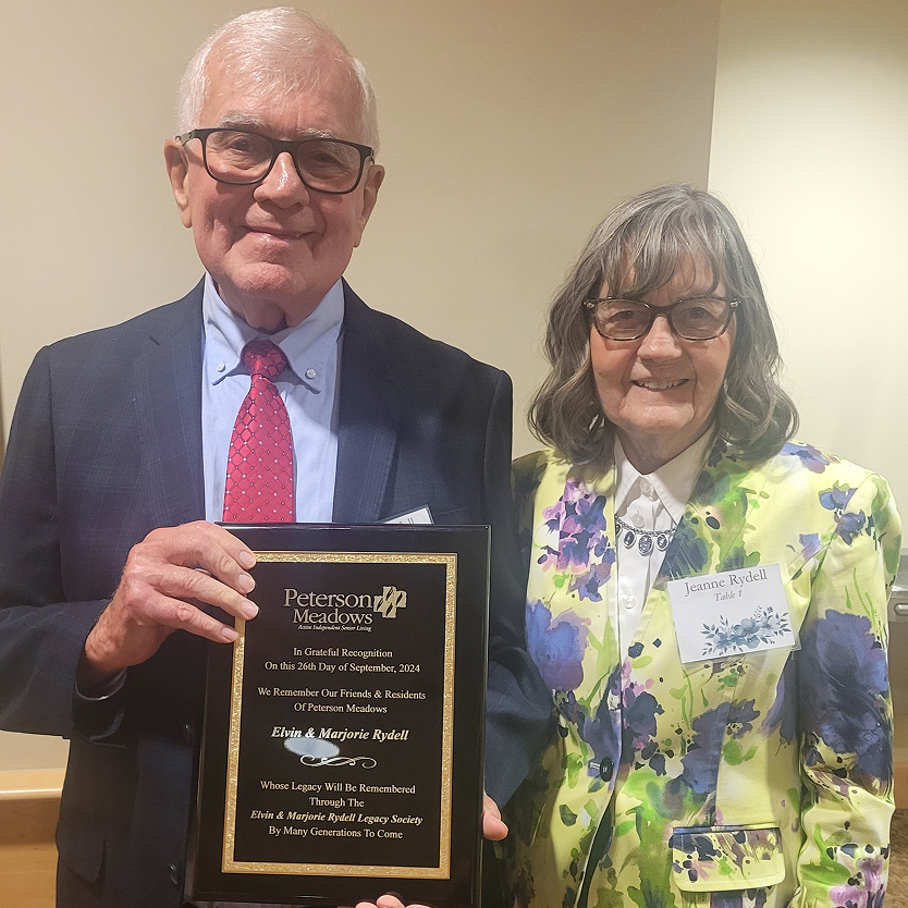 Elderly couple holding a recognition plaque at an event