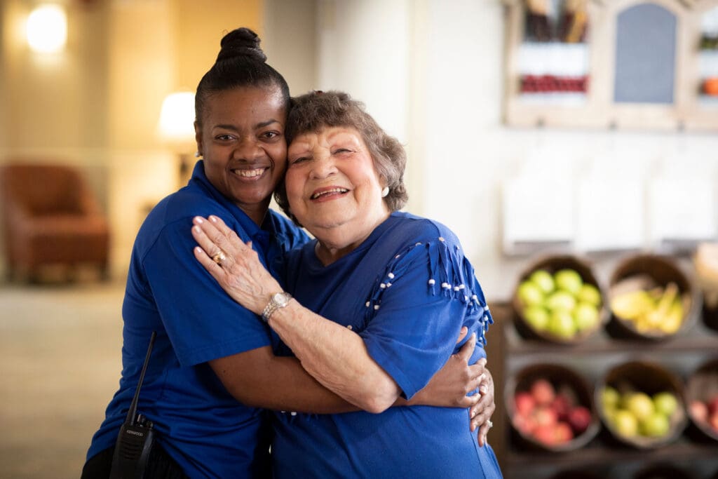 Staff member hugging a resident in a cheerful setting