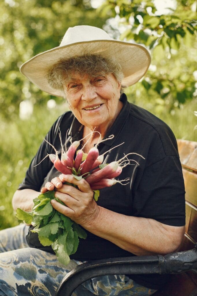 Resident smiling outdoors holding freshly harvested vegetables