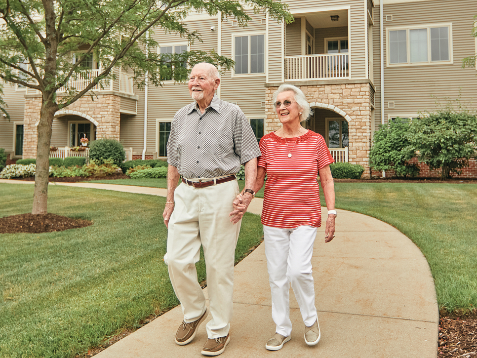 An elderly couple walking hand in hand on a pathway