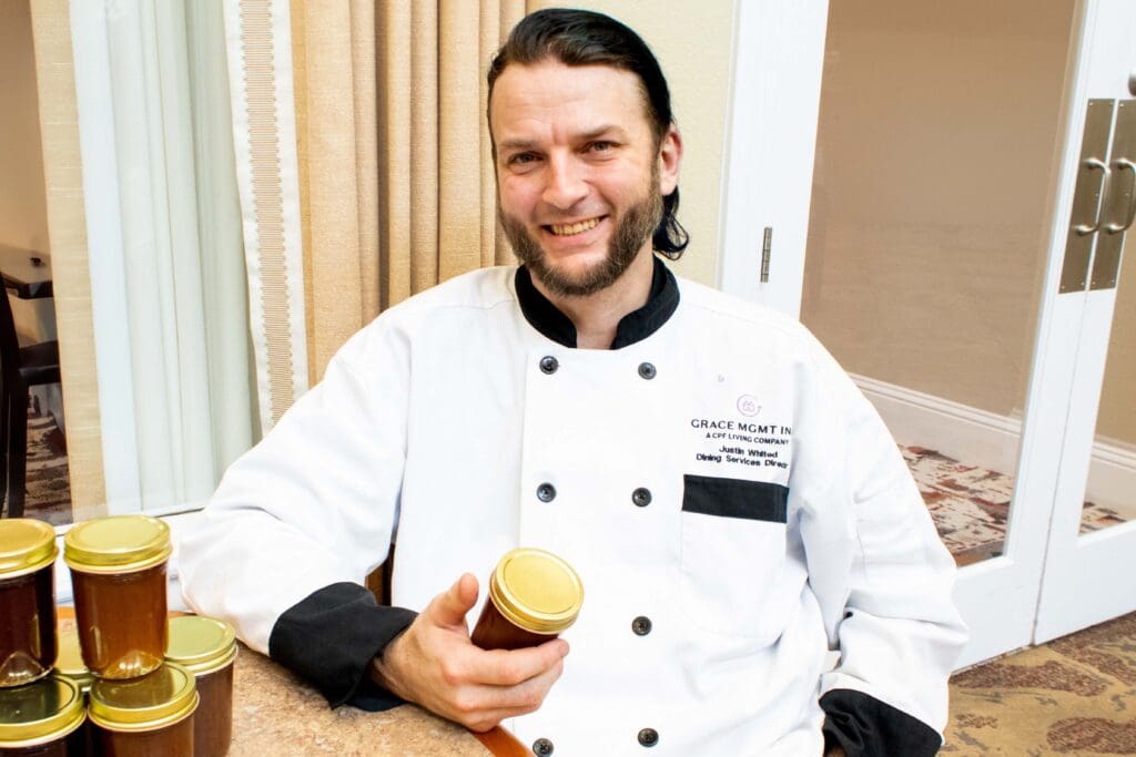Chef in a kitchen holding a jar of homemade jam