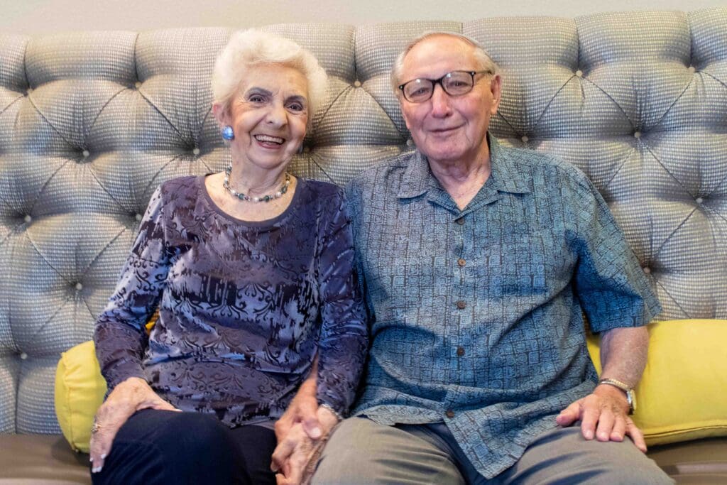 Two smiling residents posing together on a couch