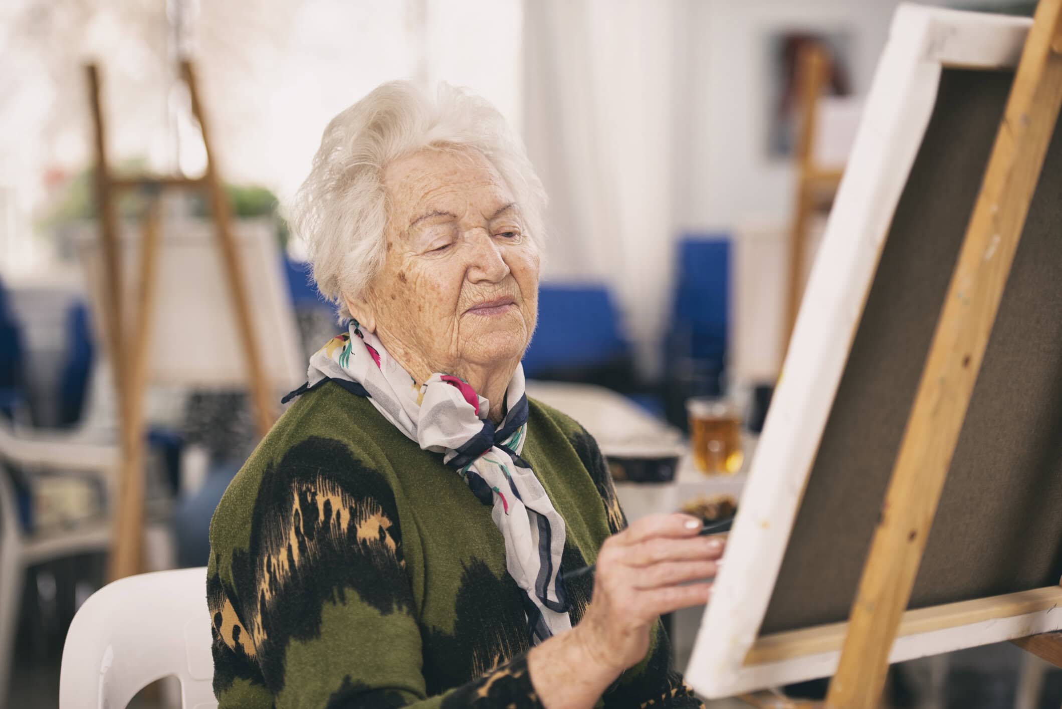 Elderly woman painting in an activity room