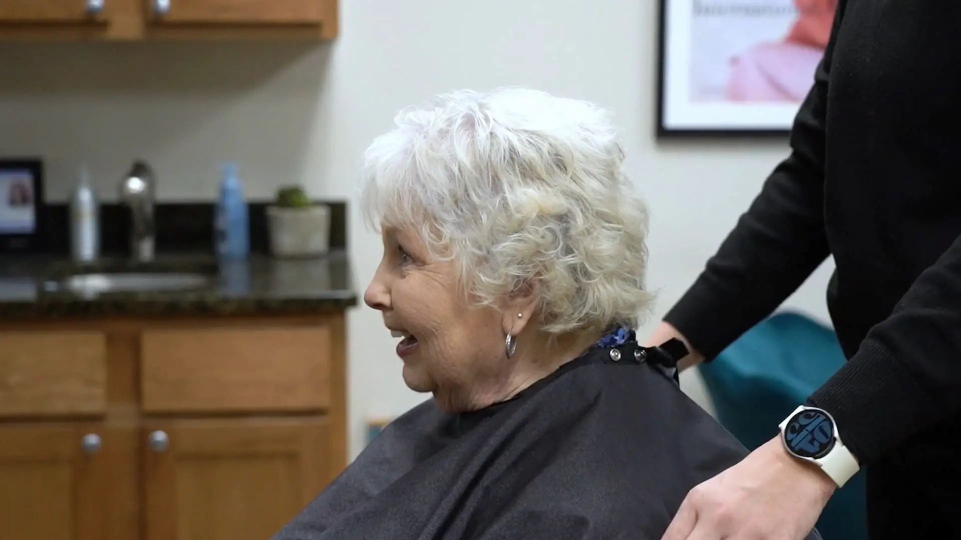 A resident enjoying a haircut with staff assistance.