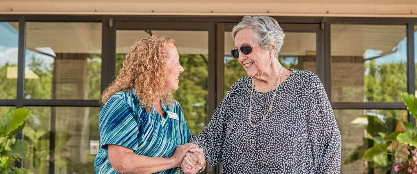 Staff member greeting a resident outside the facility