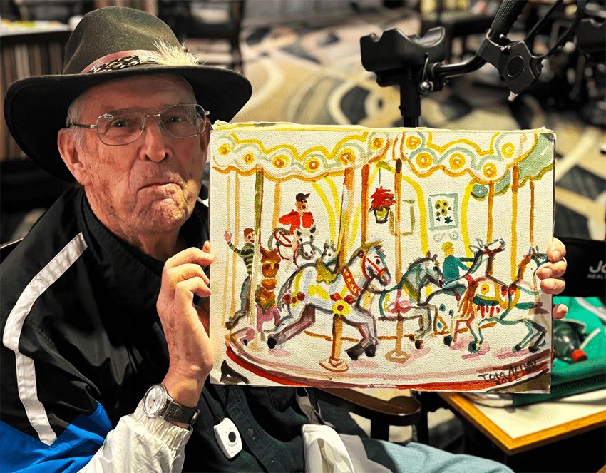 An elderly man holding a colorful painting of a carousel