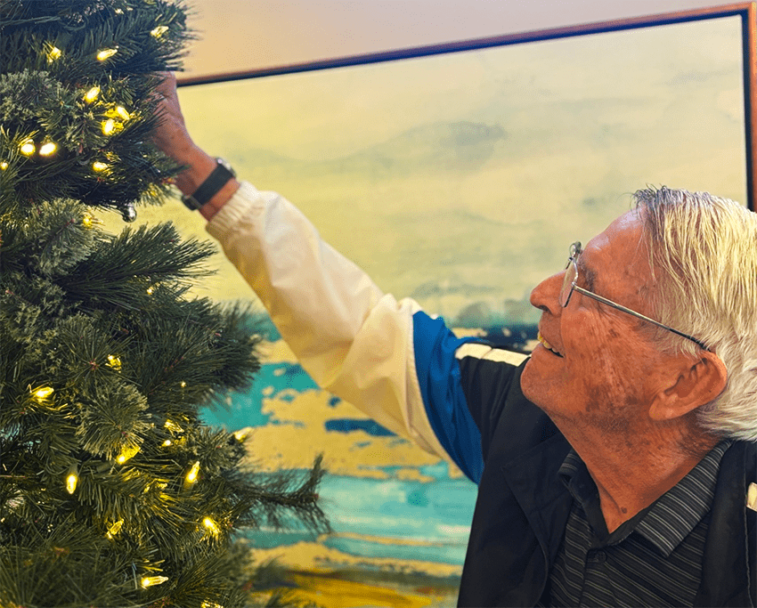 Resident decorating a Christmas tree with lights