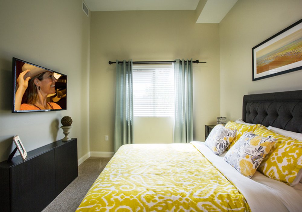 Well-decorated interior of a resident room with a bed and TV