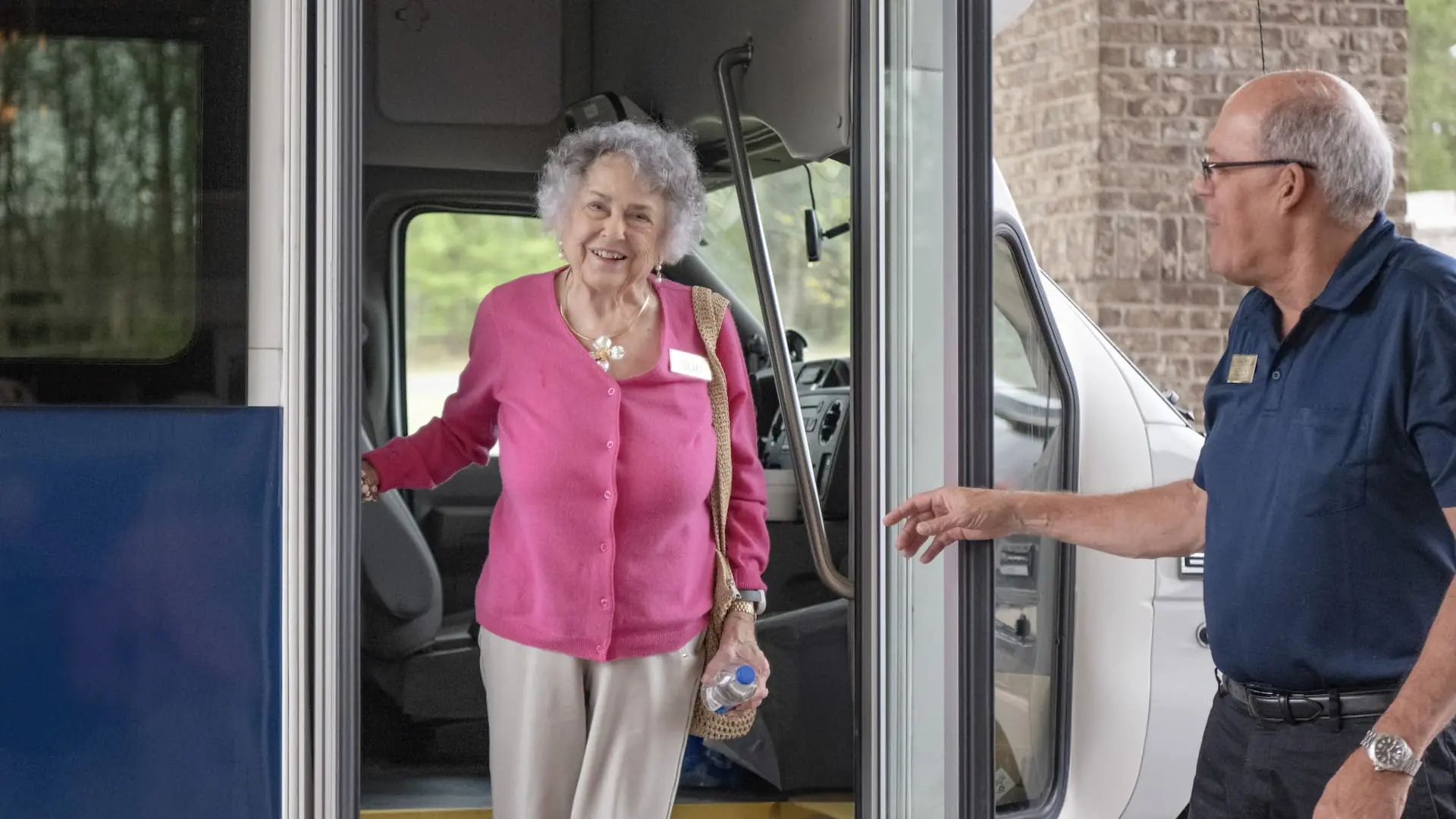 Smiling resident stepping off facility transport van