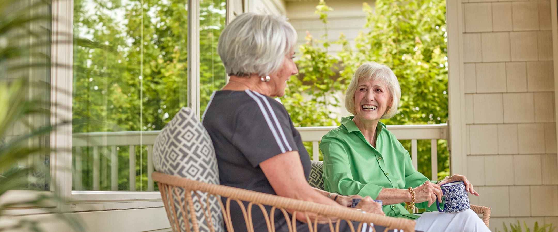 Two residents enjoying conversation on a sunny porch