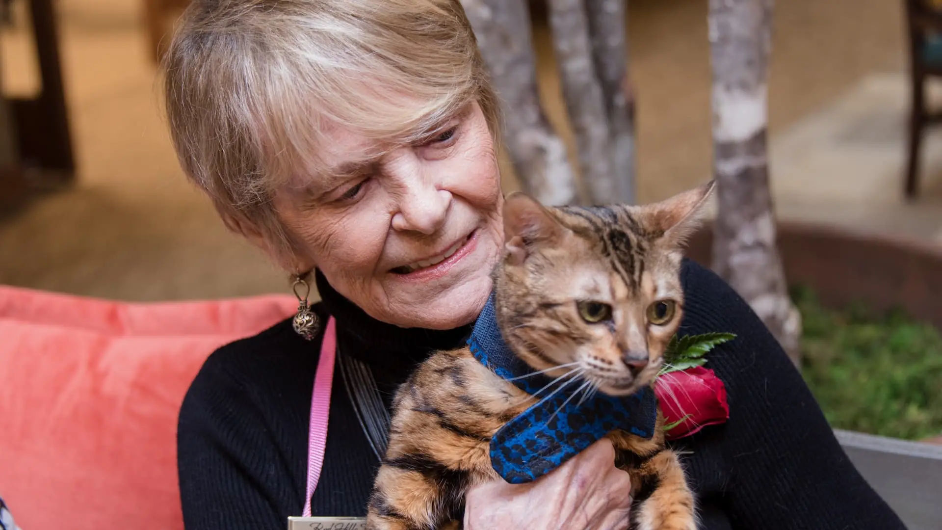 Resident holding a cat with a rose in a cozy setting