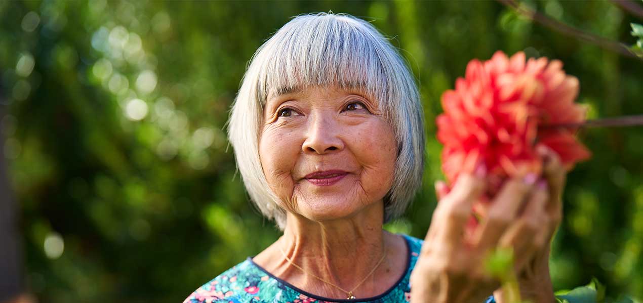 Senior woman enjoying flowers in a garden