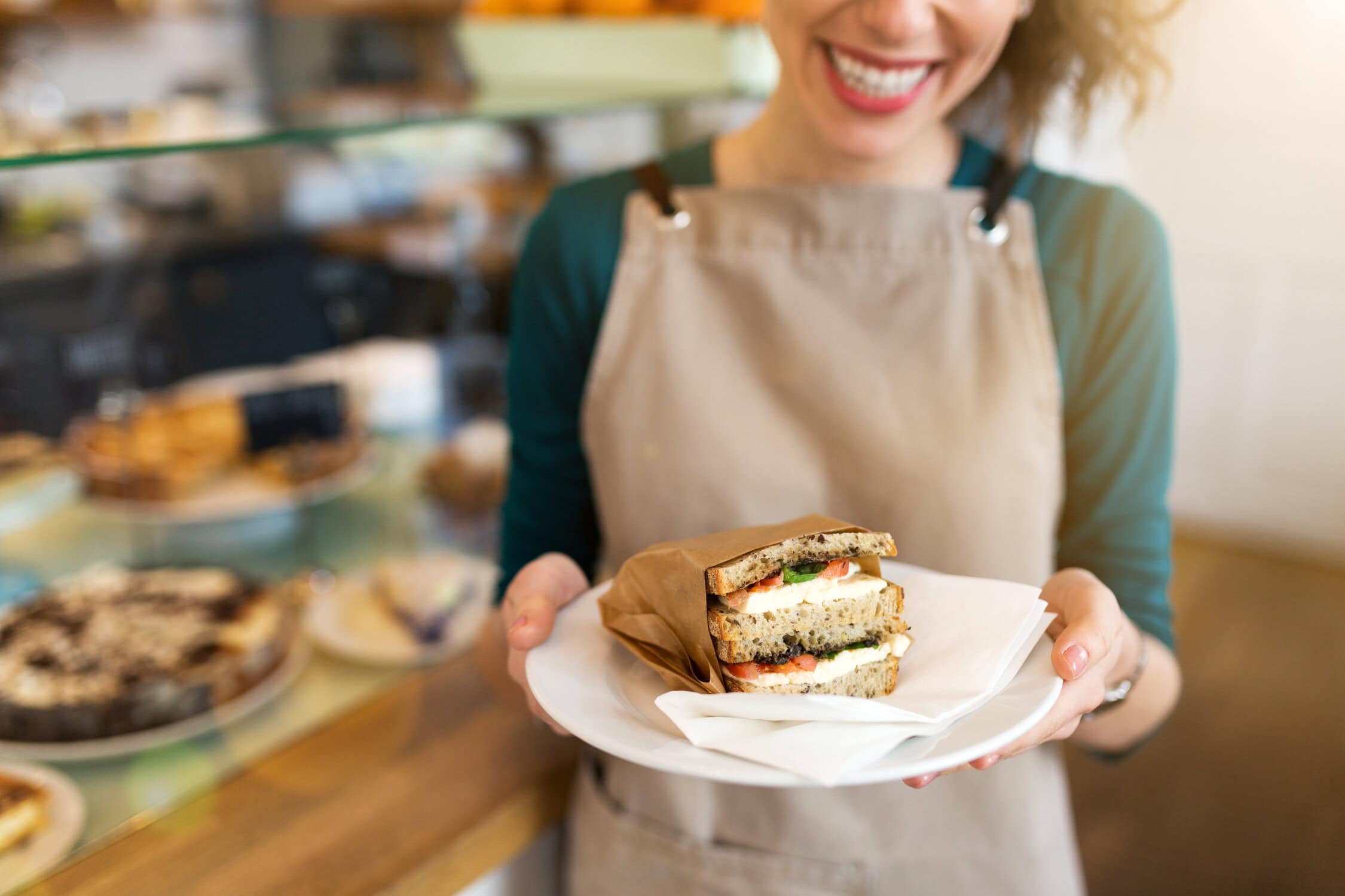 A barista presenting a sandwich in a café.